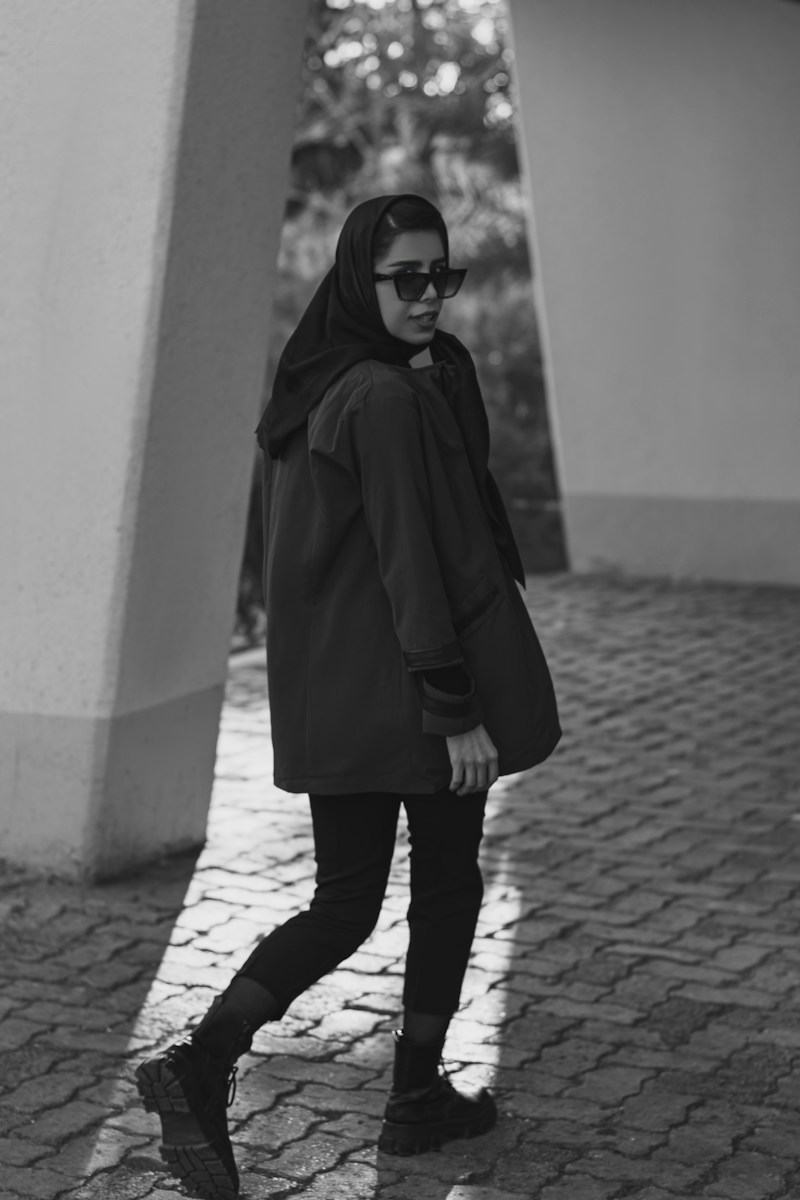 Photo by omid bonyadian a woman wearing a black coat and sunglasses