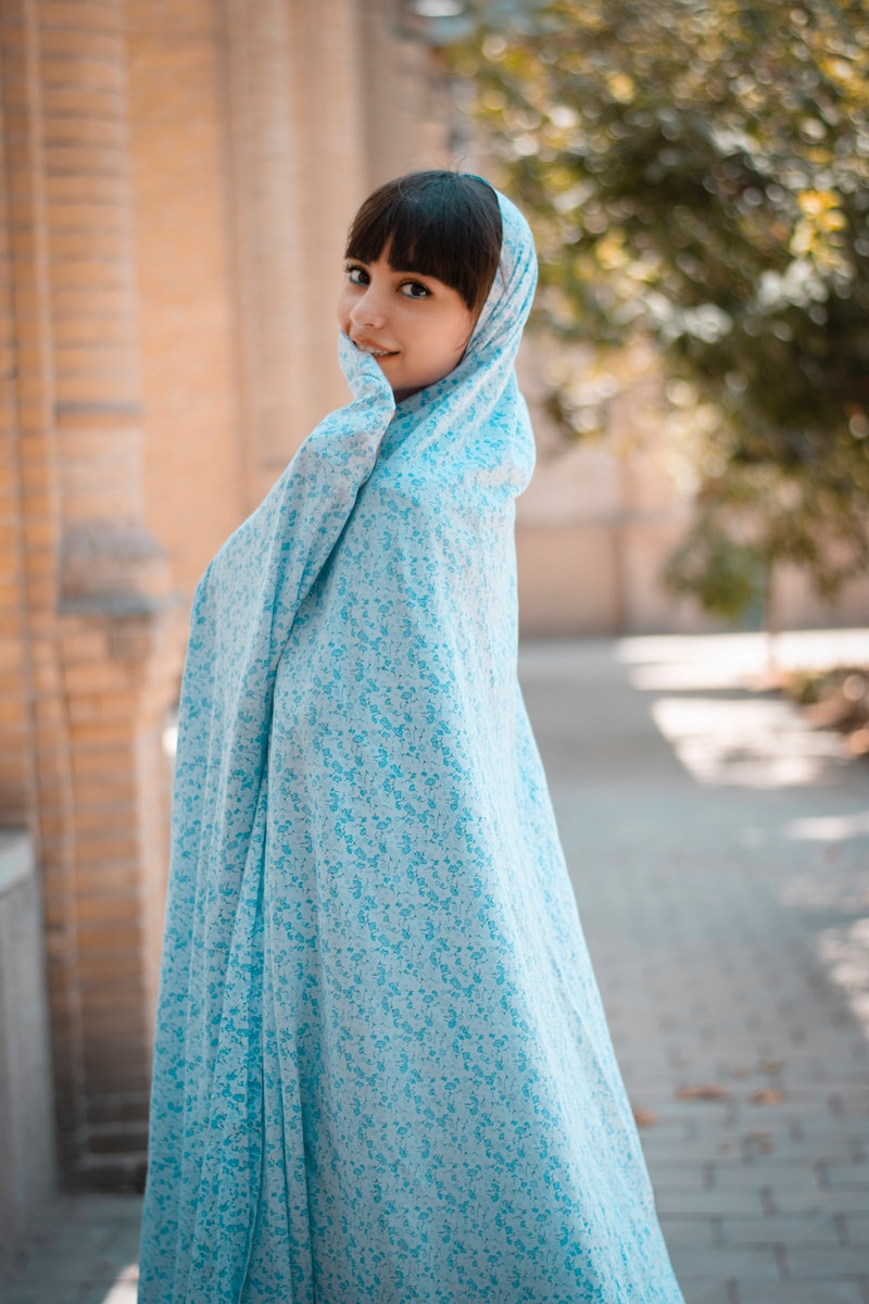 girl in blue hijab standing on sidewalk during daytime